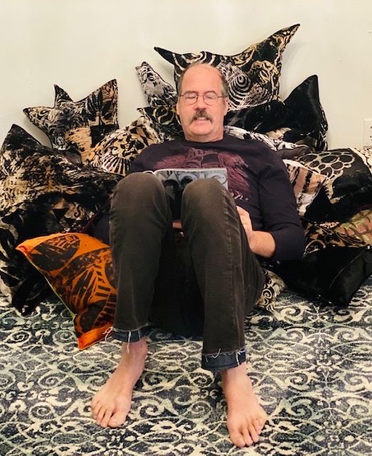 Krist with laptop leaning on pillows.
